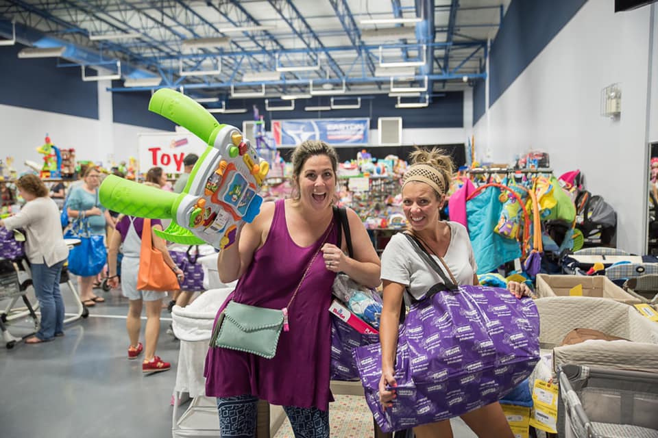 Two friends shop together—one mom wears her baby girl—as they find great deals at their local JBF sale.