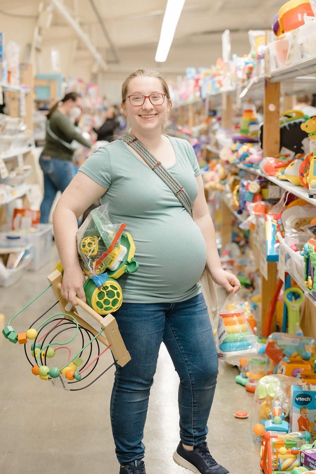 An expecting mom holding a baby seat.
