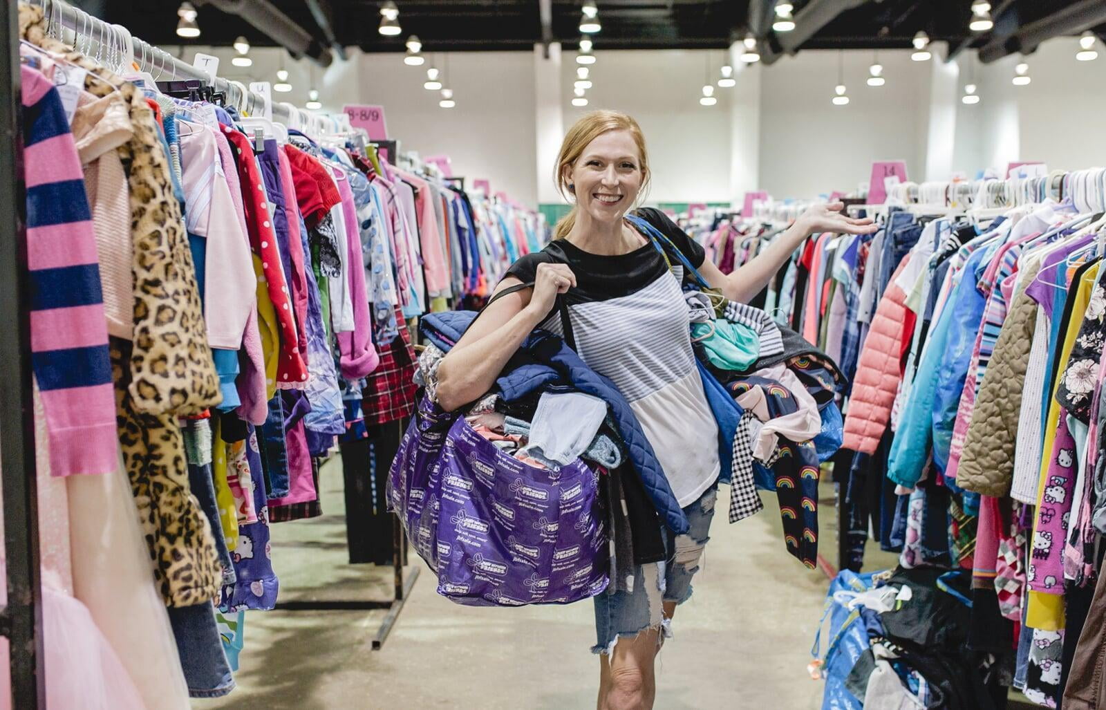 A mom and grandmother stand beside a rack of clothing at a JBF sale in Texas.