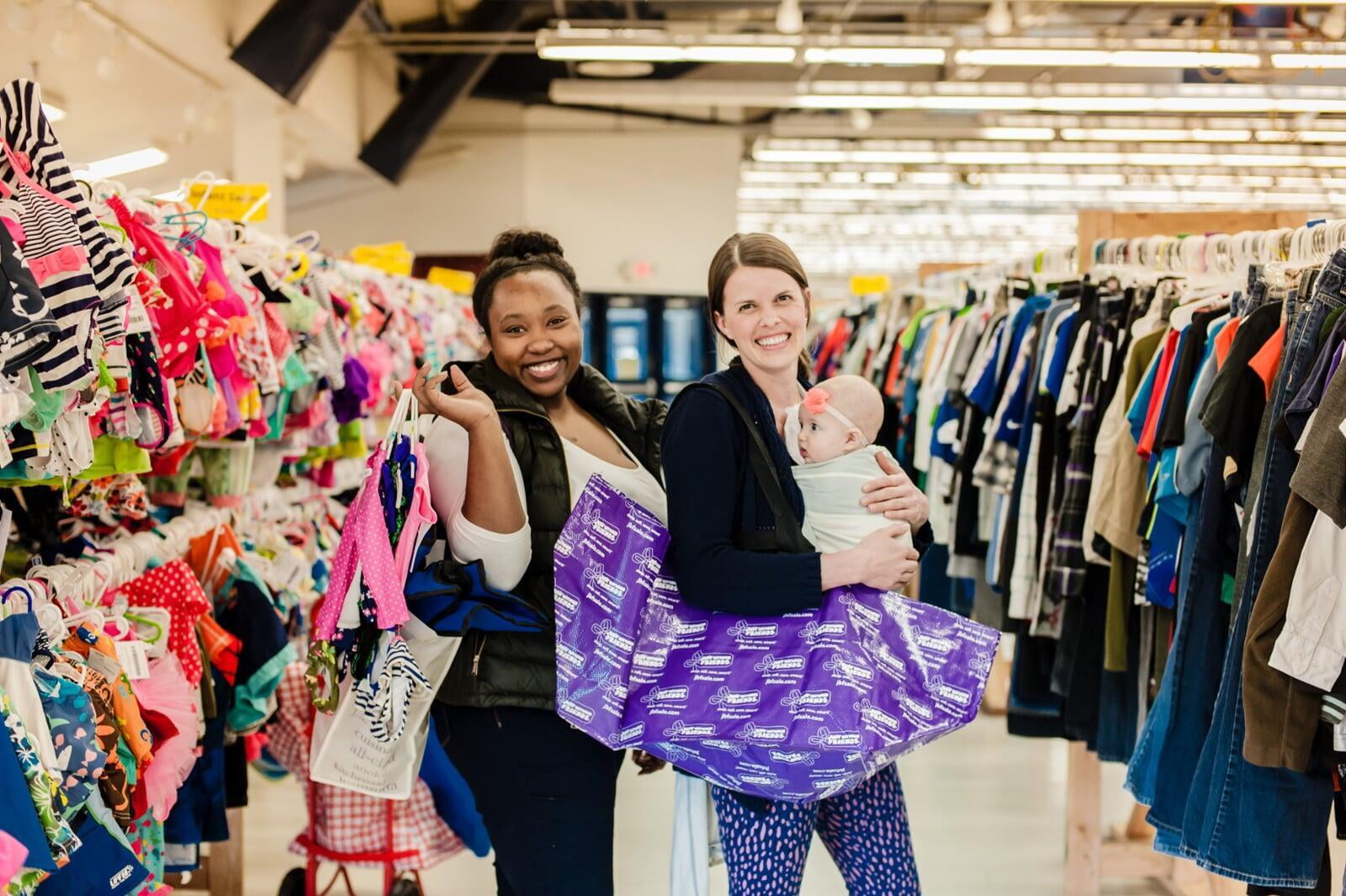 Three young girls are excited to shop together in the toy section of their local JBF sale.
